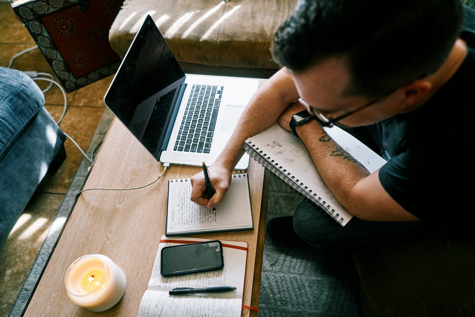 man in black t-shirt writing on white paper